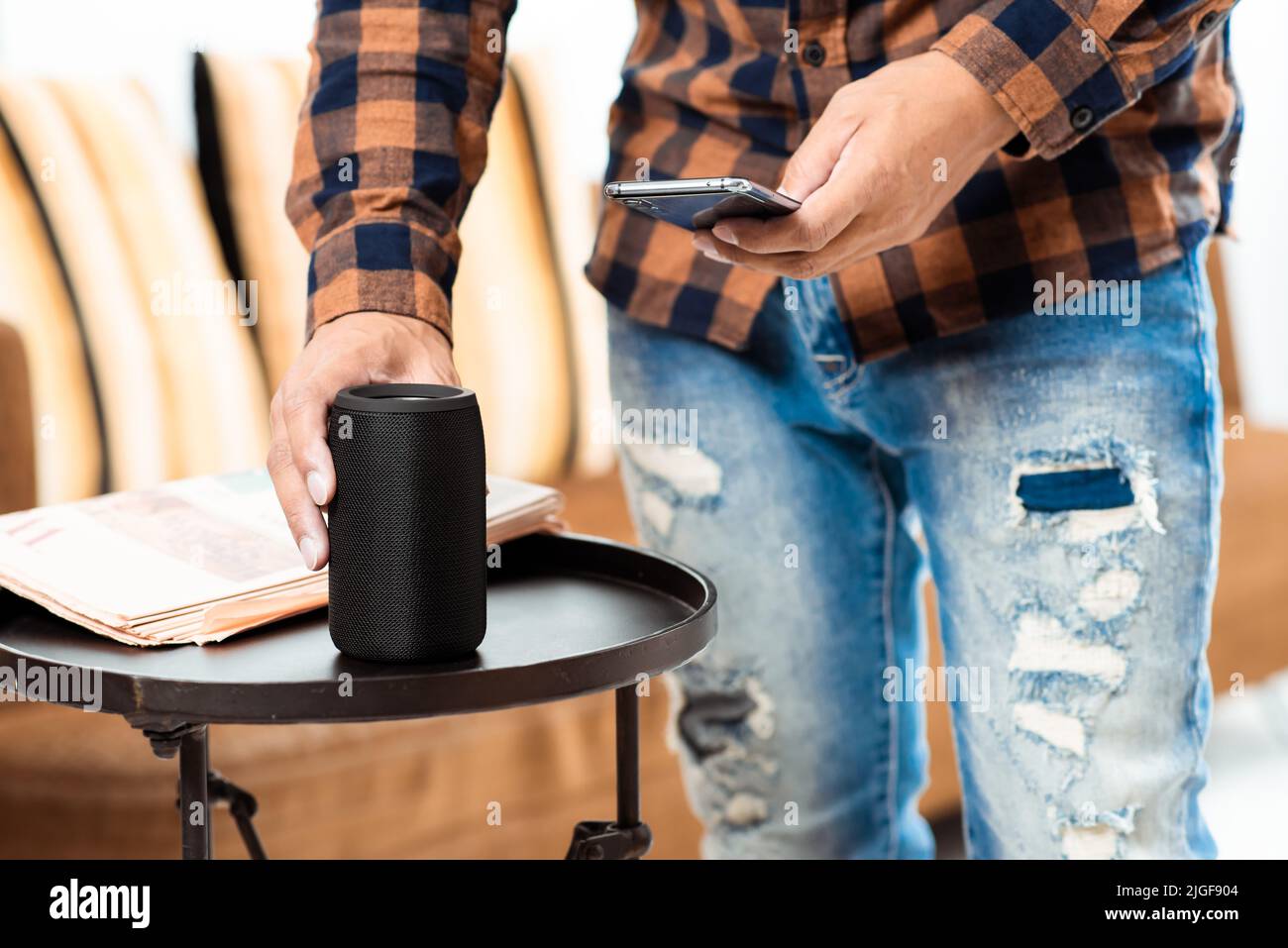 The man streams music from smartphone to bluetooth speaker. Stock Photo