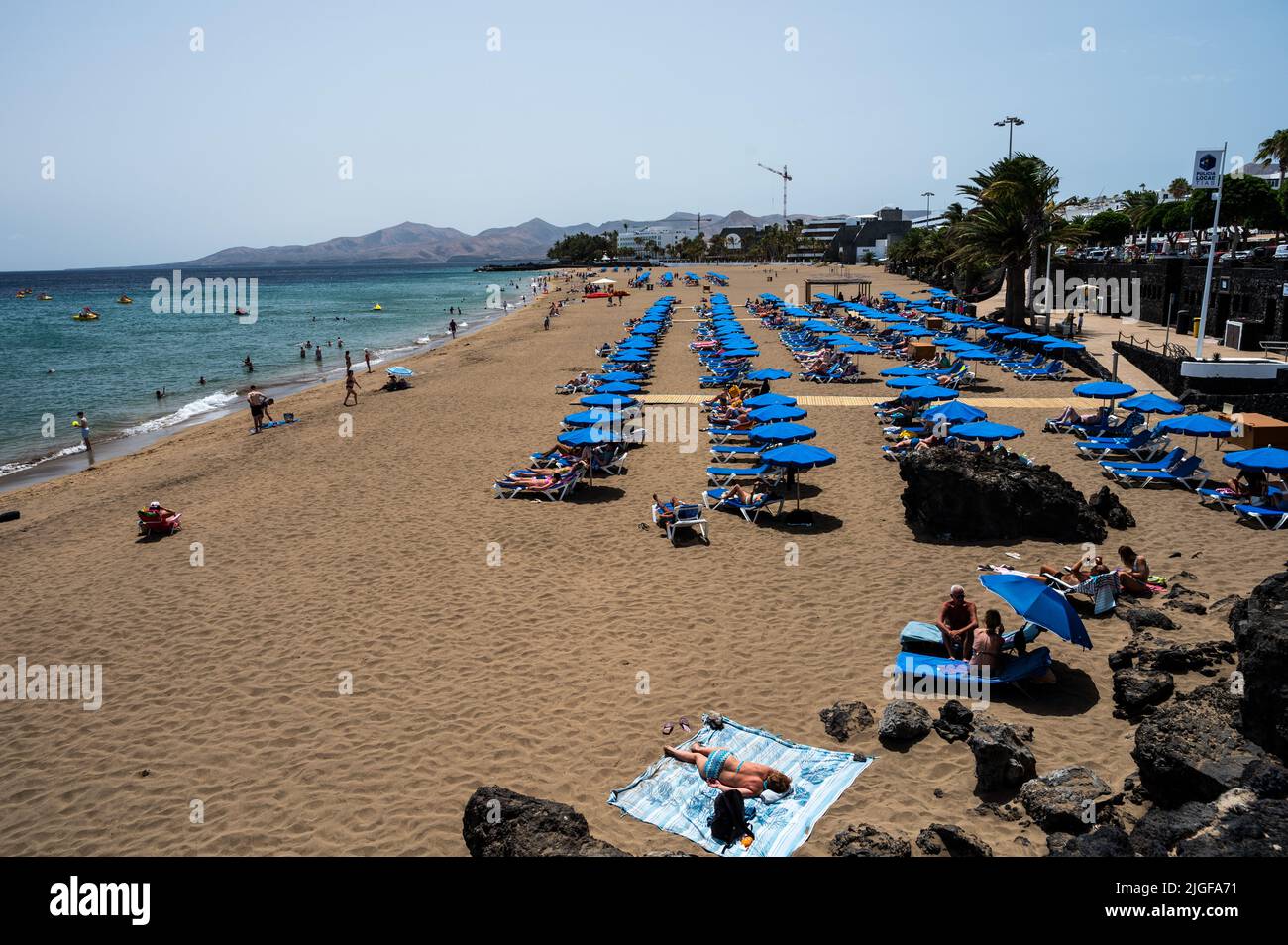 Tourists sunbathe, swim and relax at Playa Grande Beach in Puerto del