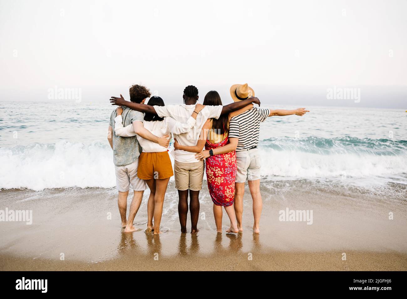 Group of young people hugging each other and enjoying summer at beach Stock Photo