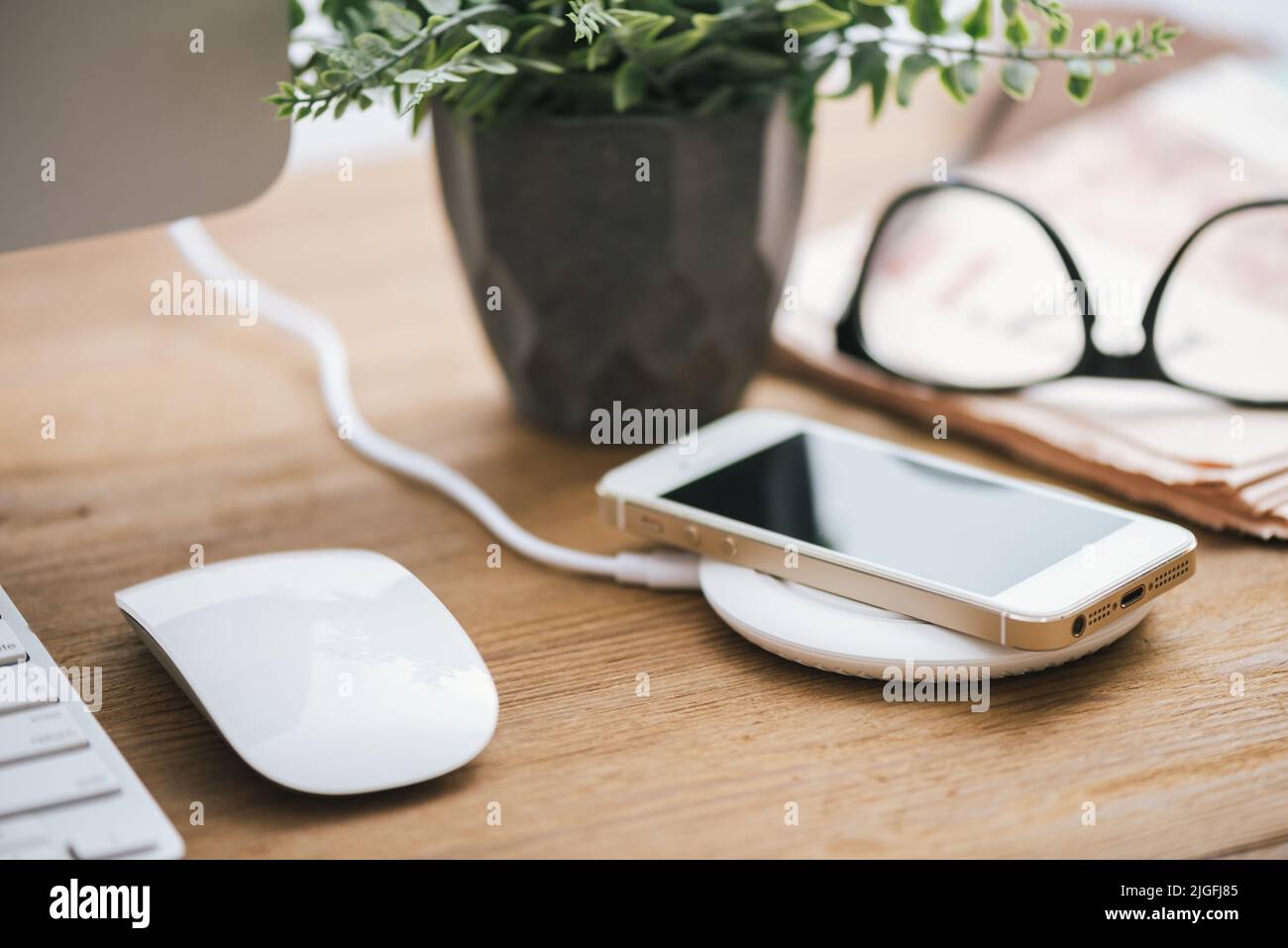 Charging the smartphone with wireless charger on desktop. Stock Photo