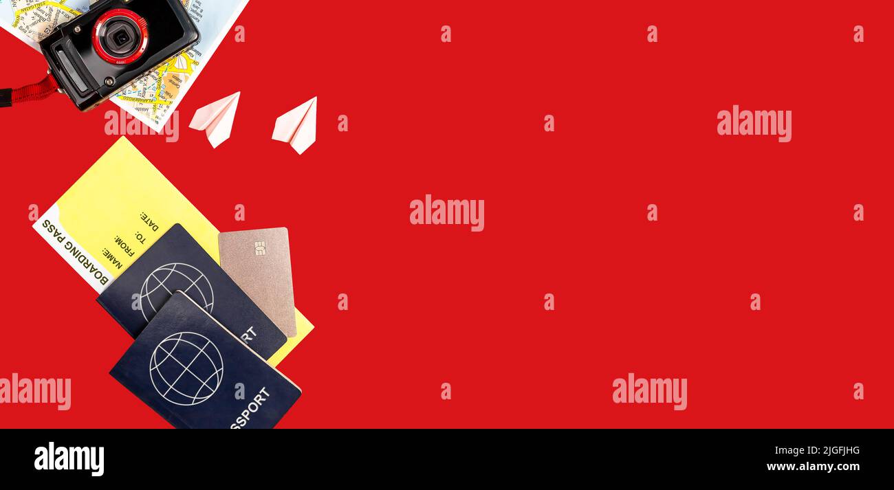 Banner with travel by couple or family trip essentials on red background. Two passports, boarding pass, credit card, tourist map, point and shoot camera, origami planes. Copy space. High quality photo Stock Photo