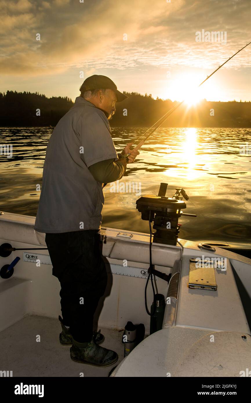 WA20628-00....WASHINGTON - Phil Russell reals in  his fishing line to check for a snag while trolling for salmon in the Puget Sound. MR# R8 Stock Photo