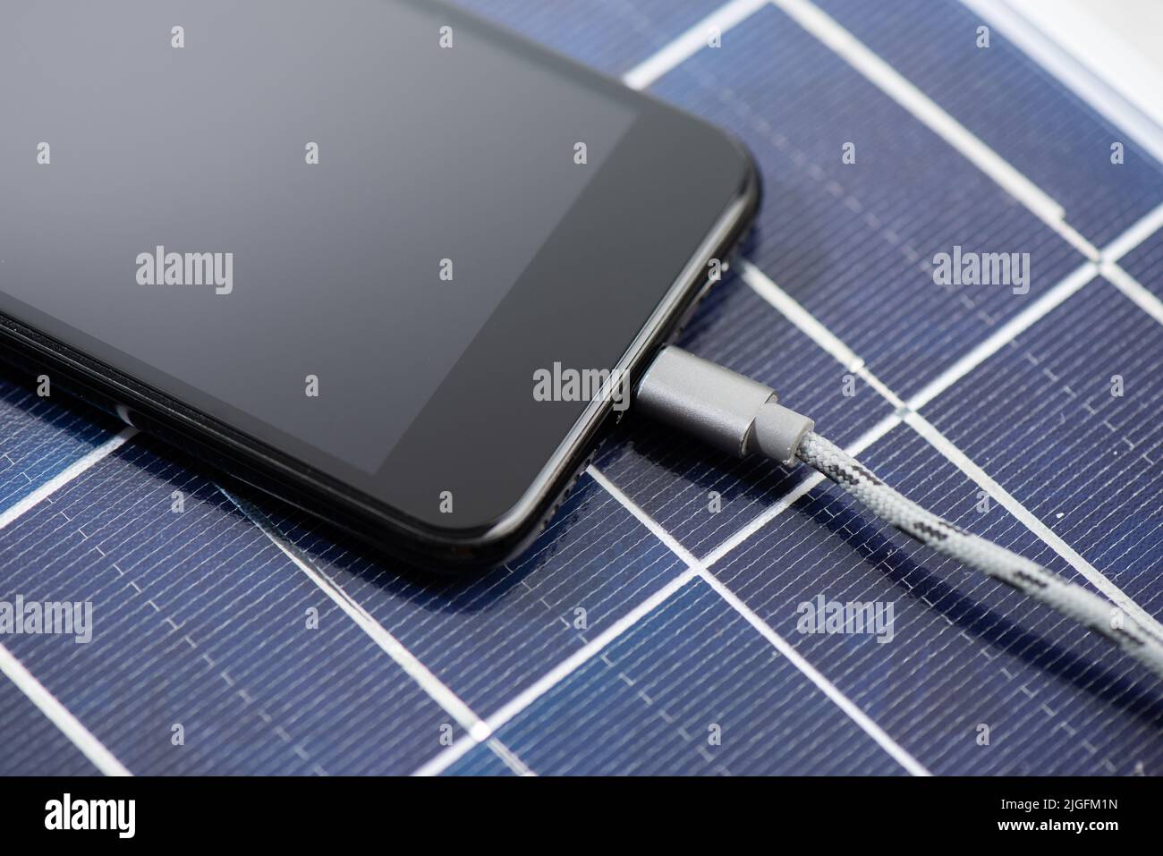 Charging the smartphone with solar energy. Green energy concept. Stock Photo