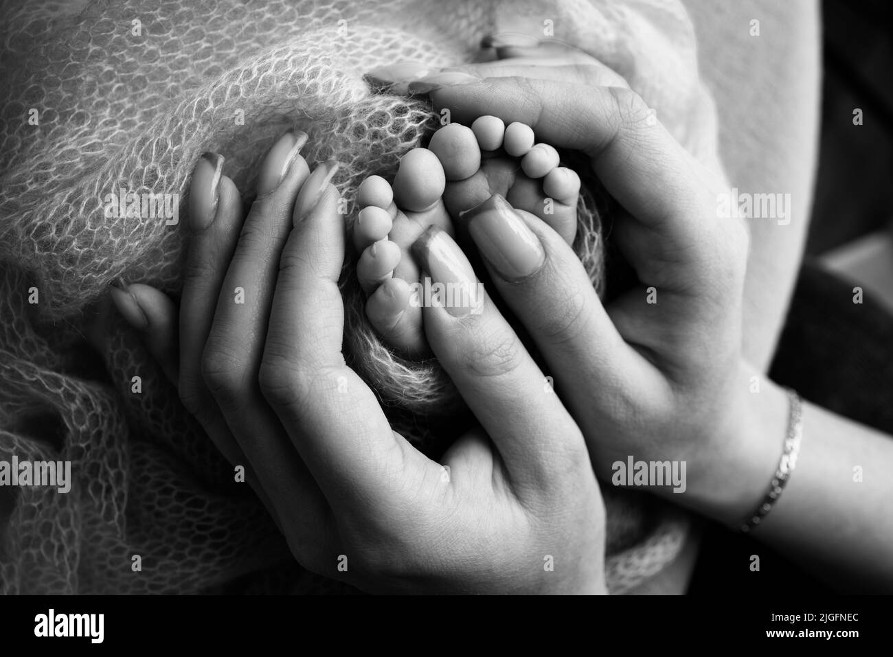 The palms of the father, the mother are holding the foot of the newborn baby. Feet of baby on the palms of the parents.  Stock Photo