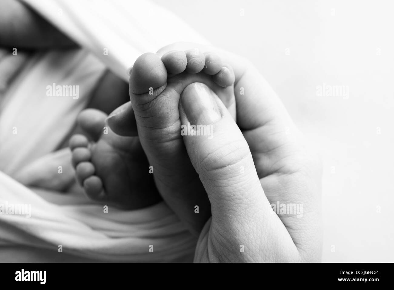 The palms of the father, the mother are holding the foot of the newborn