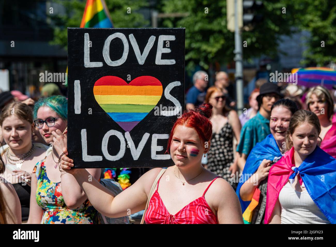 Love is Love. Woman holding a sign on her shoulder at Helsinki Pride 2022 Parade in Helsinki, Finland. Stock Photo