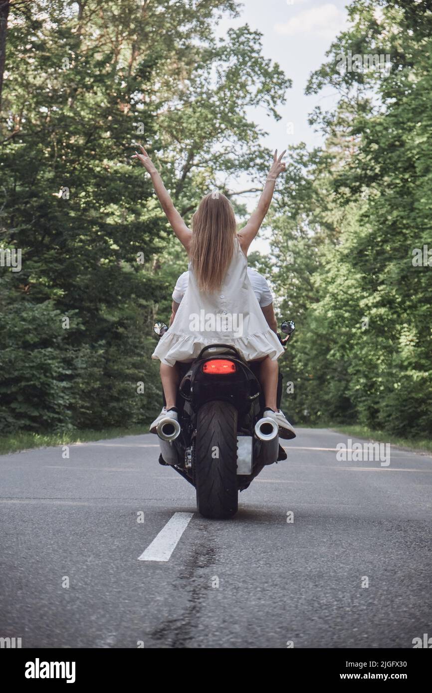 Happy Motorcycle Rider A young happy couple rides a motorcycle on an asphalt road in the ...