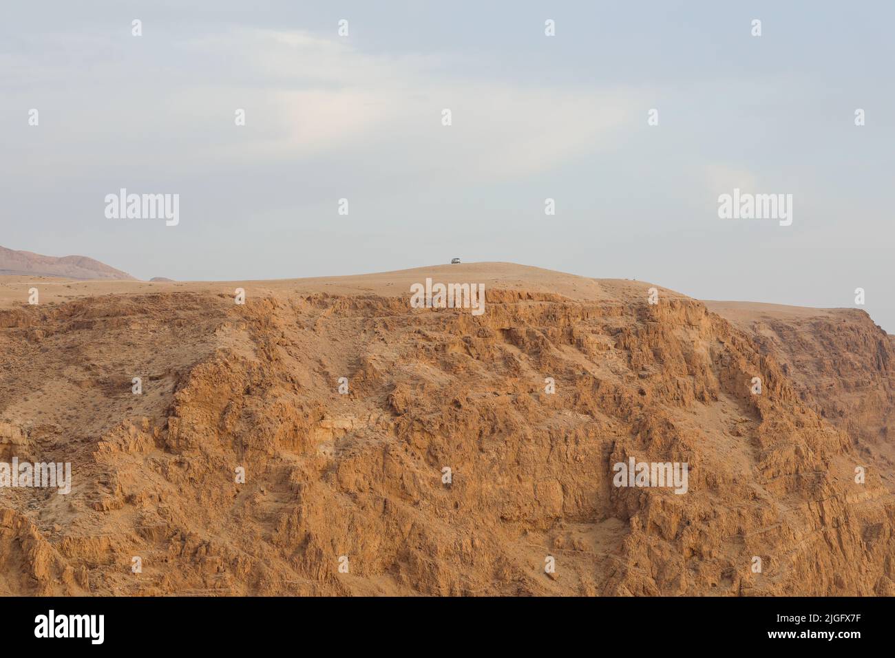 Car parking at the top of a cliff in a desert landscape. Distance view. Stock Photo
