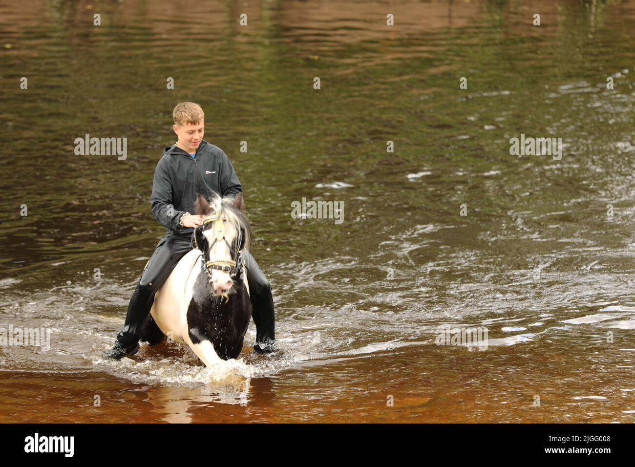 A teenage boy riding his horse in the River Eden, Appleby Horse Fair ...
