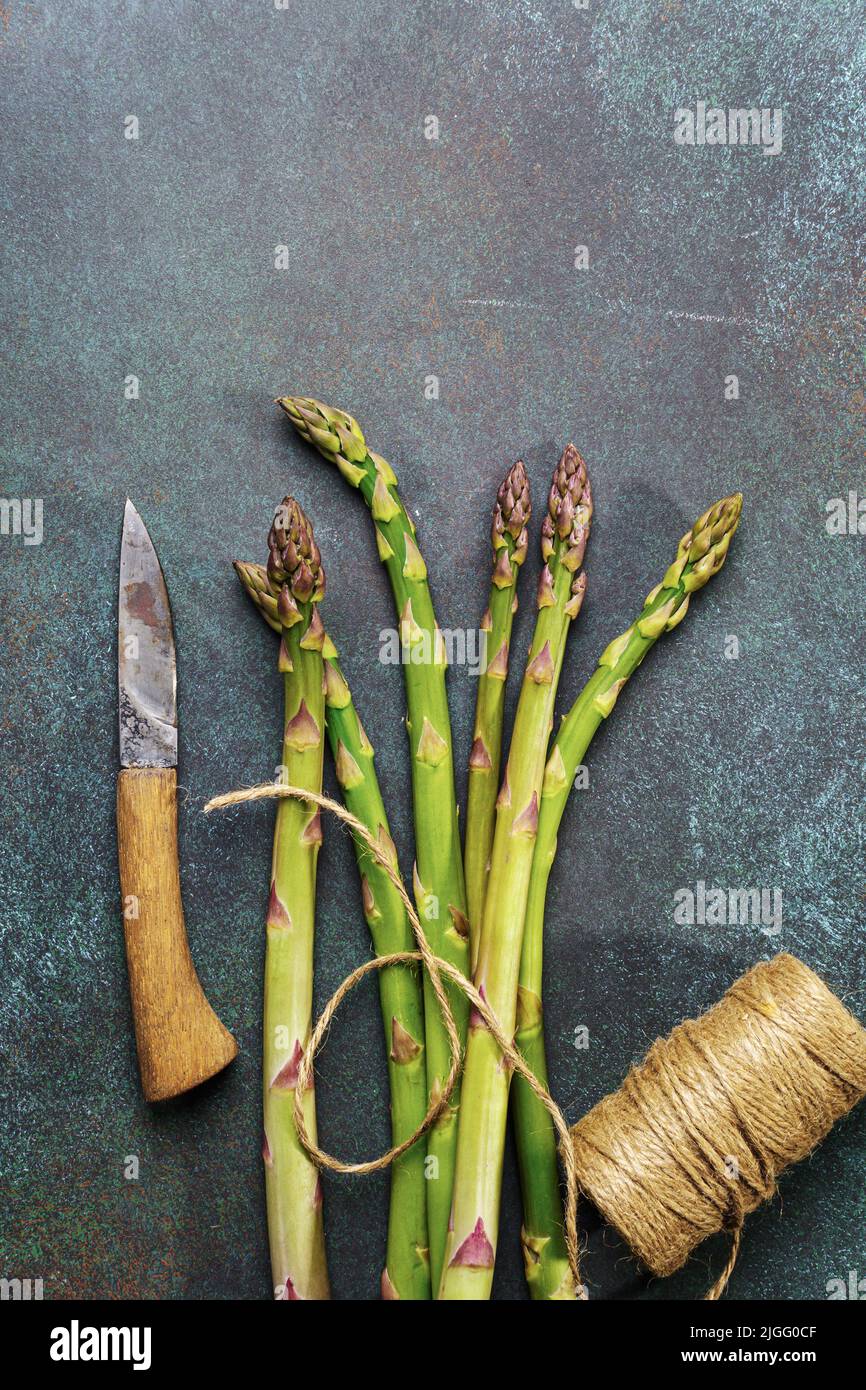 Ripe organic asparagus with rope and knife on dark background. Stock Photo