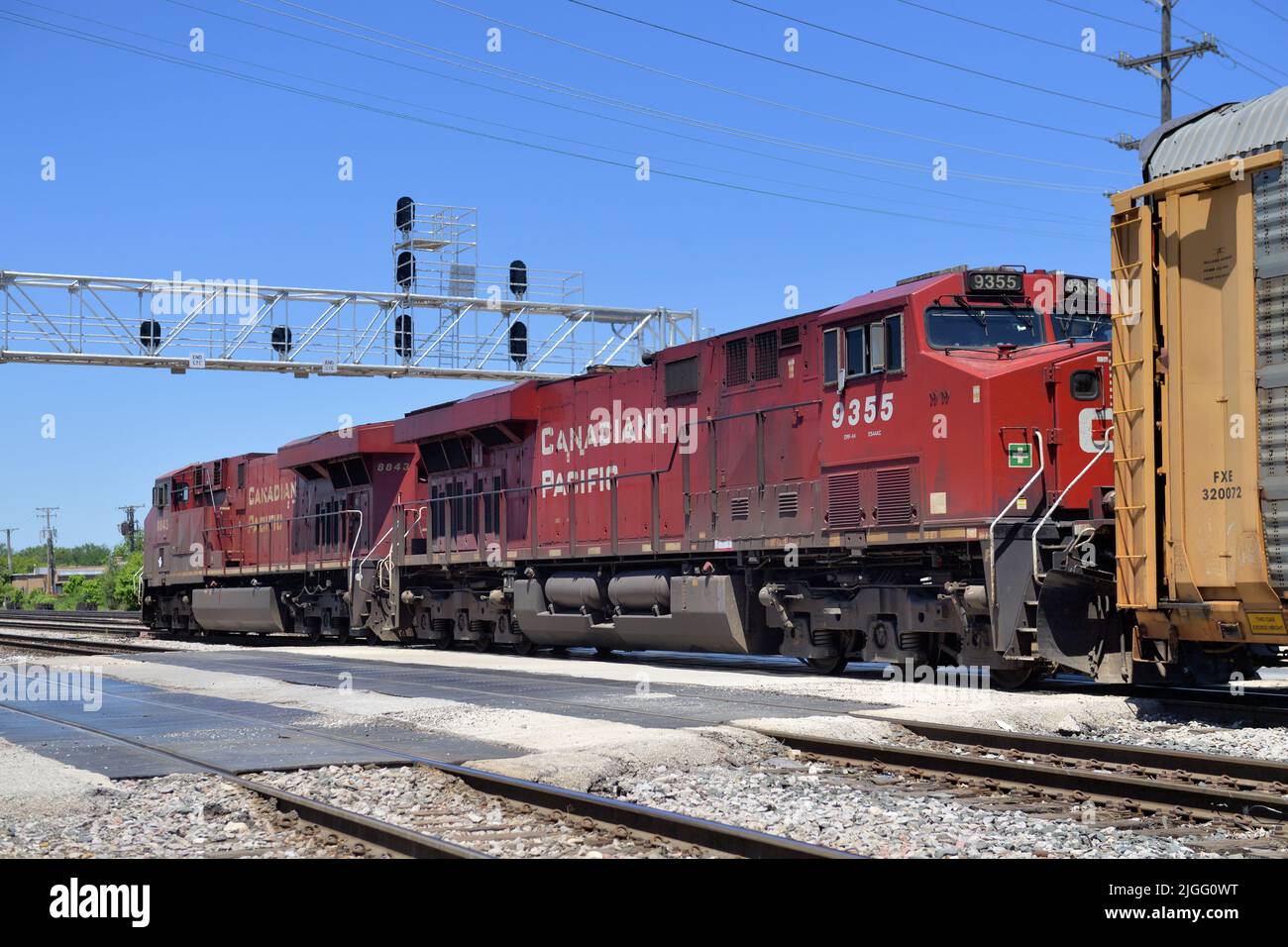 Franklin Park, Illinois, USA. Canadian Pacific Railway locomotives lead a freight train through a street crossing and under a signal bridge. Stock Photo