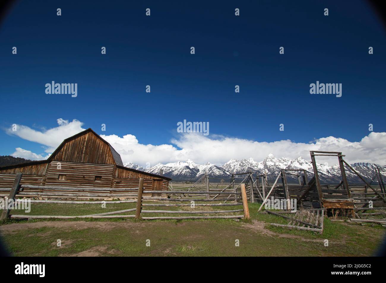 Snow-covered Teton Range serves as a backdrop for a barn at the Mormon Row Historic District in Grand Teton NP, WY. Stock Photo