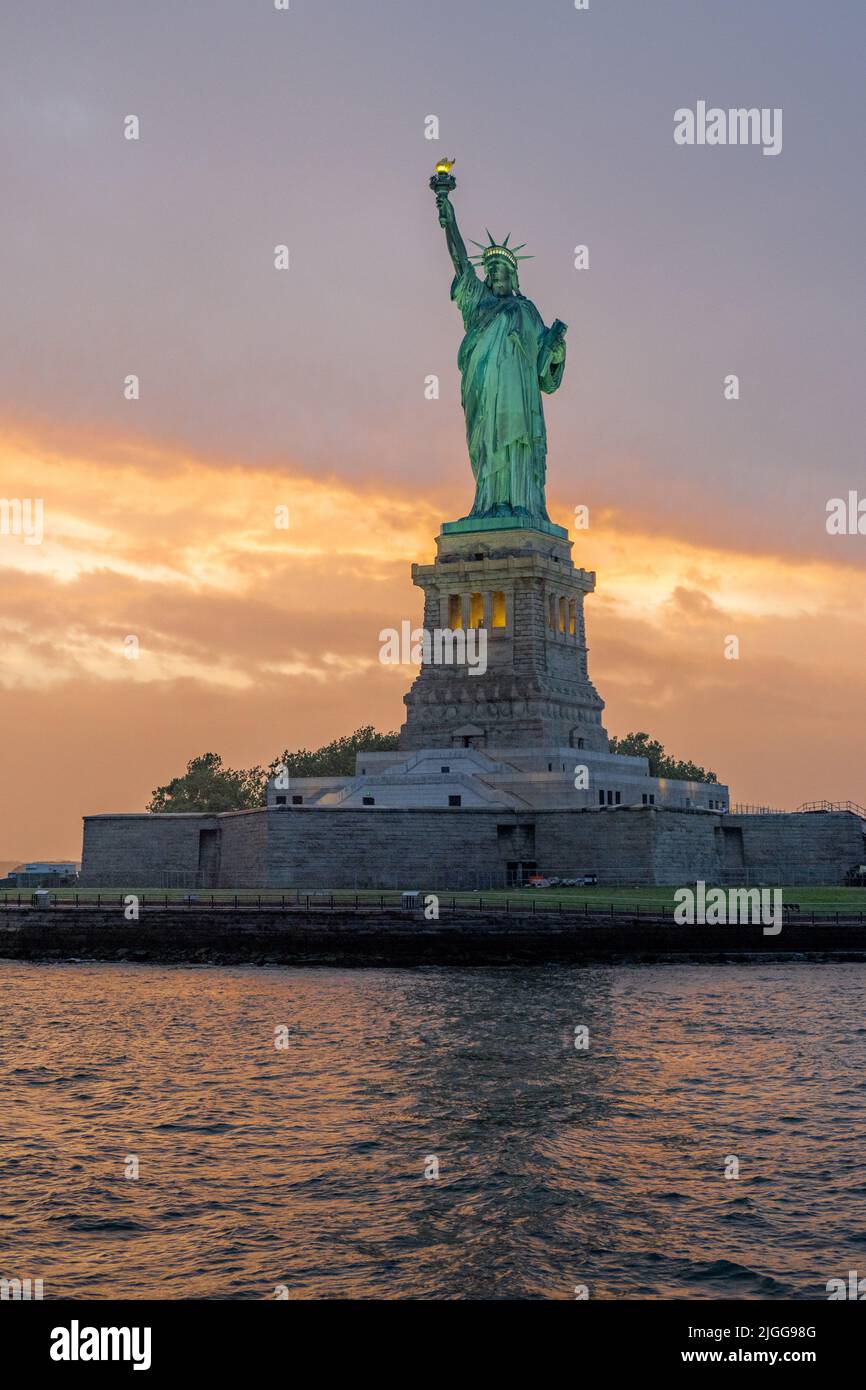 Statue of liberty, New York, USA, during the golden hour with a cloudy sky in the background Stock Photo