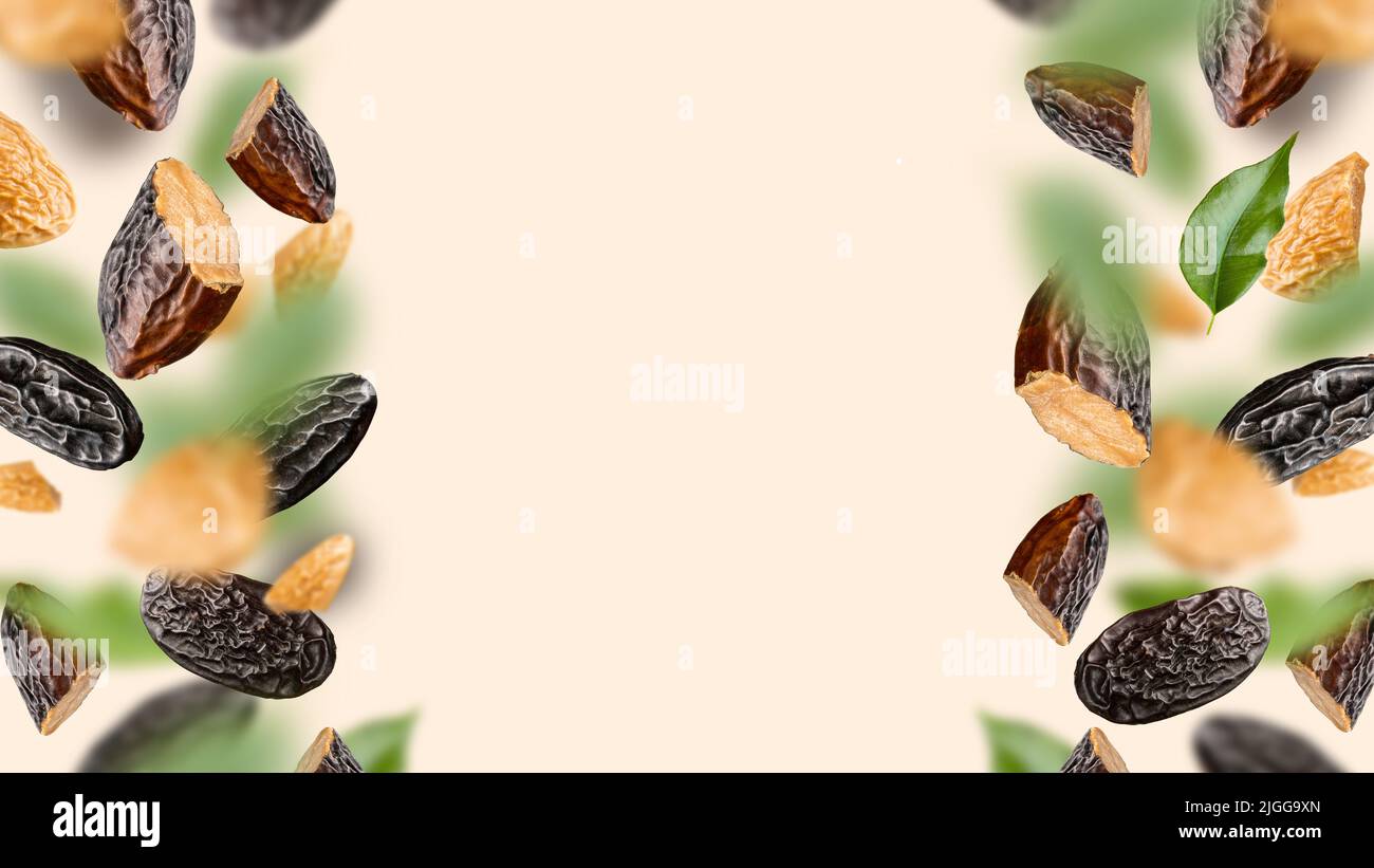 Tonka beans and green leaves float on a beige background. Dipteryx odorata is known as tonka