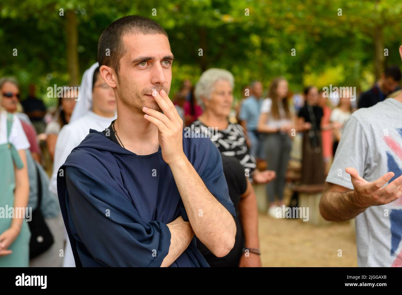 A young friar, among other pilgrims, listening to a catechesis or a prayer during Mladifest 2021 – the youth festival – in Medjugorje. Stock Photo