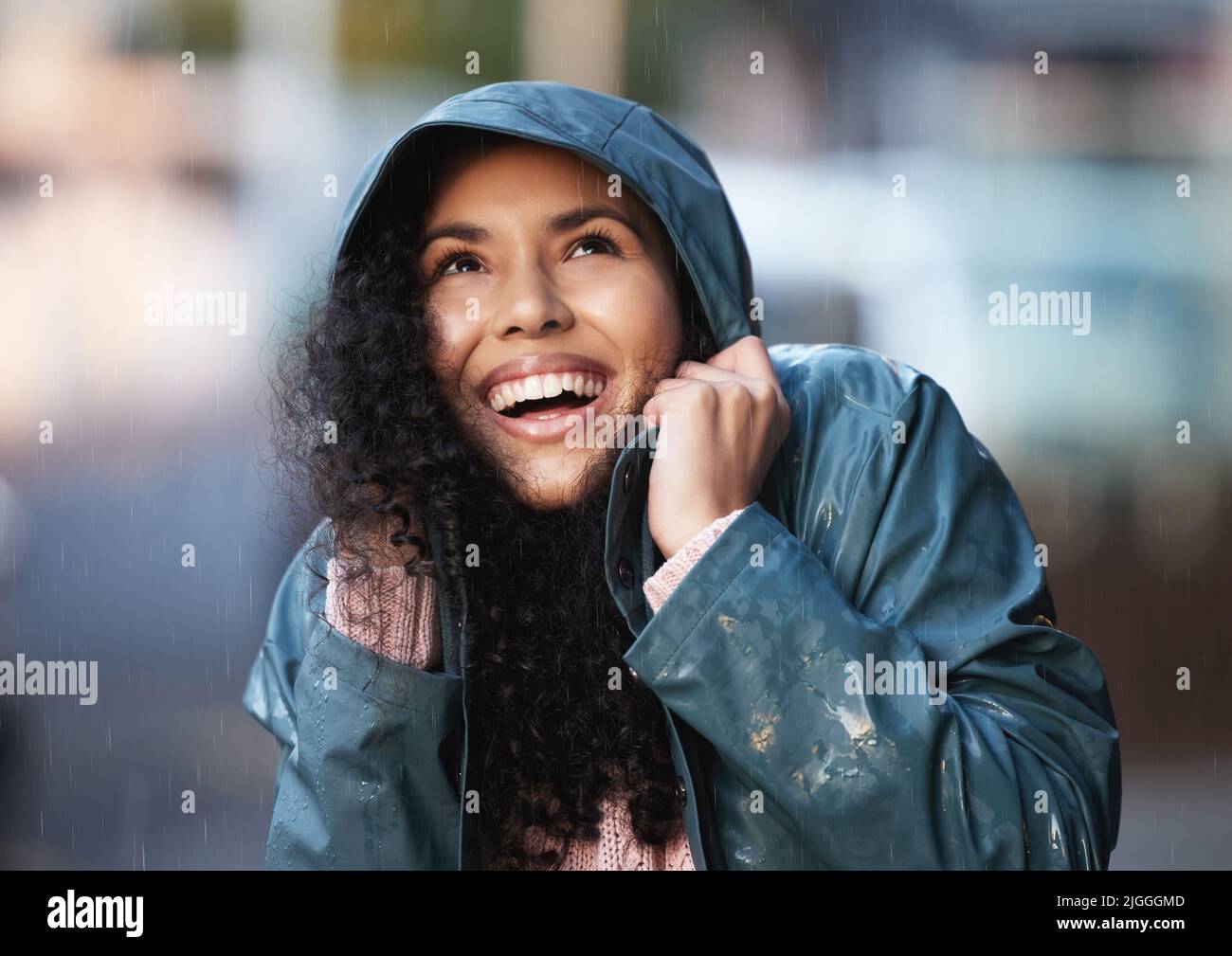 This weather sure is something. a young woman admiring the rain in the city. Stock Photo