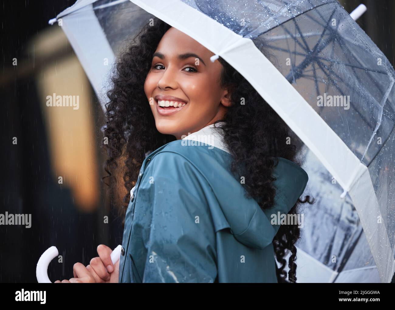 This really is my kind of weather. a young woman holding an umbrella in the city. Stock Photo