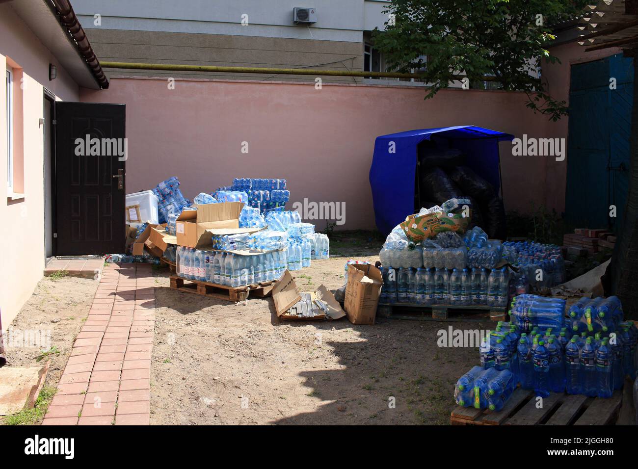 A large number of water bottles is seen on the street. Previously, the building was used for extracurricular education of children in creativity and biology. Since the beginning of the war between Russia and Ukraine, a volunteer center has been operating in these premises, dealing with the distribution of humanitarian aid from EU. Stock Photo