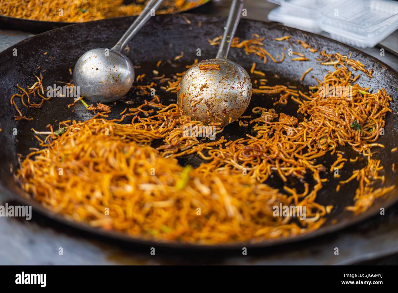 Fried Noodles in a pan on a street food market in Kuala Lumpur, Malaysia. Selective Focus on the trowel. Street food markets a famous and well known f Stock Photo