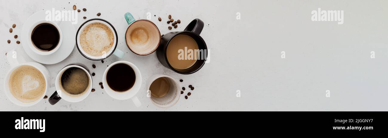 Top view on flat lay with many different full and empty coffee cups composition on gray white concrete background. Variety of tea mug collection layout. Dried coffee beans. Espresso, latte, americano Stock Photo