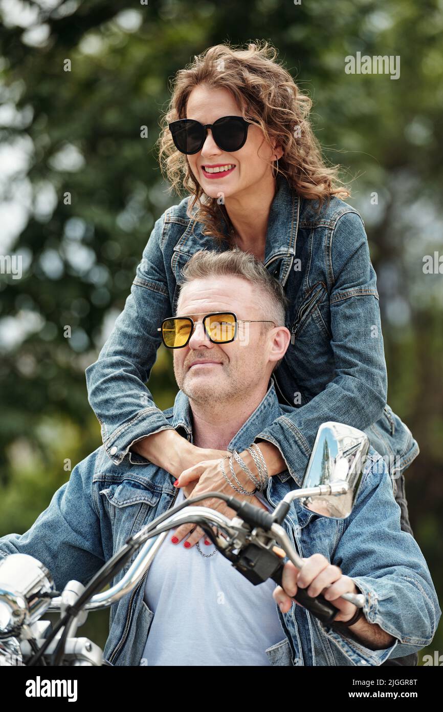 Progressive mature couple having active retirement, they are riding motorcycle in city Stock Photo