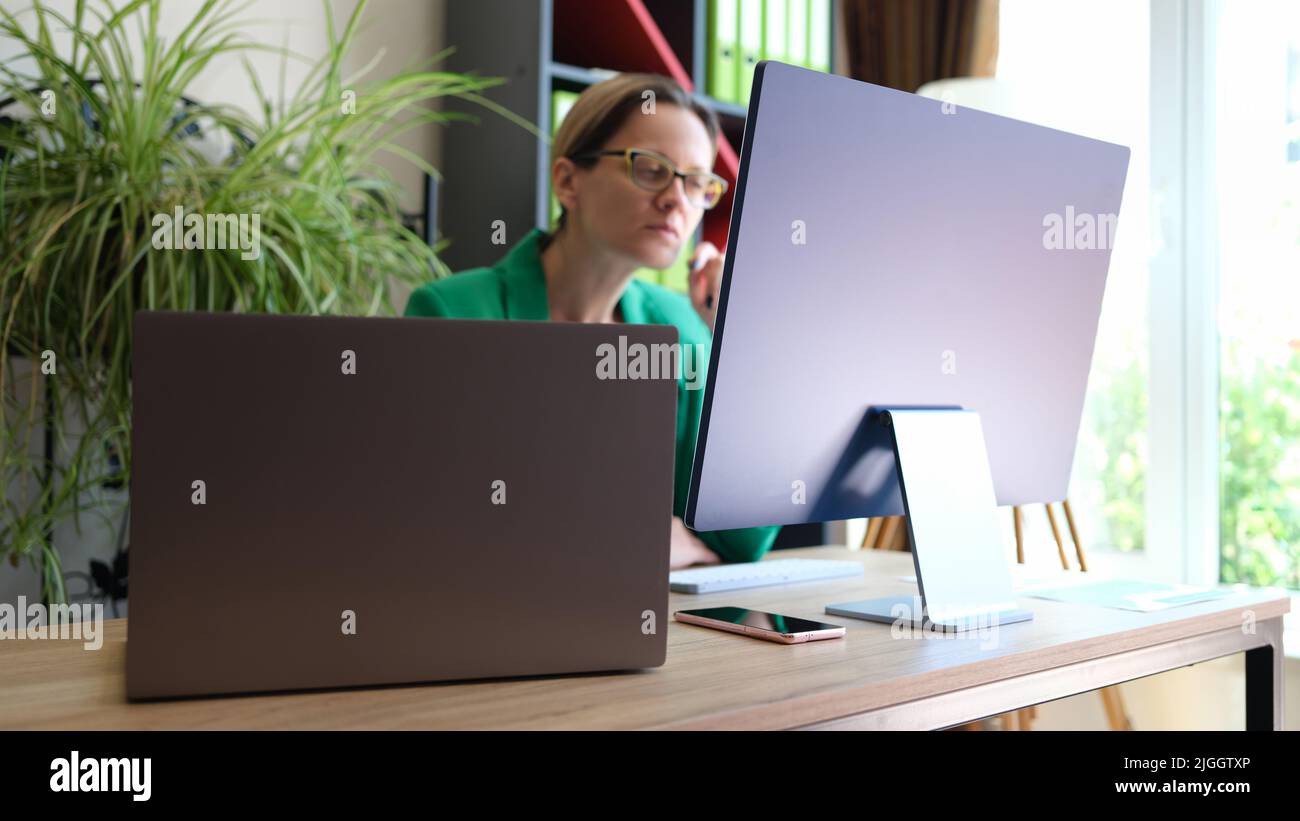 Woman office worker sitting at workplace and working using pc Stock Photo