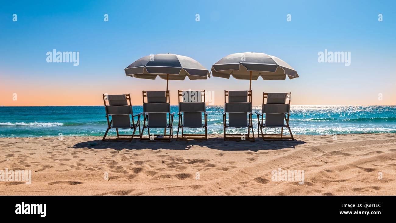 Beach chairs with parasol on a beautiful summer day. Stock Photo