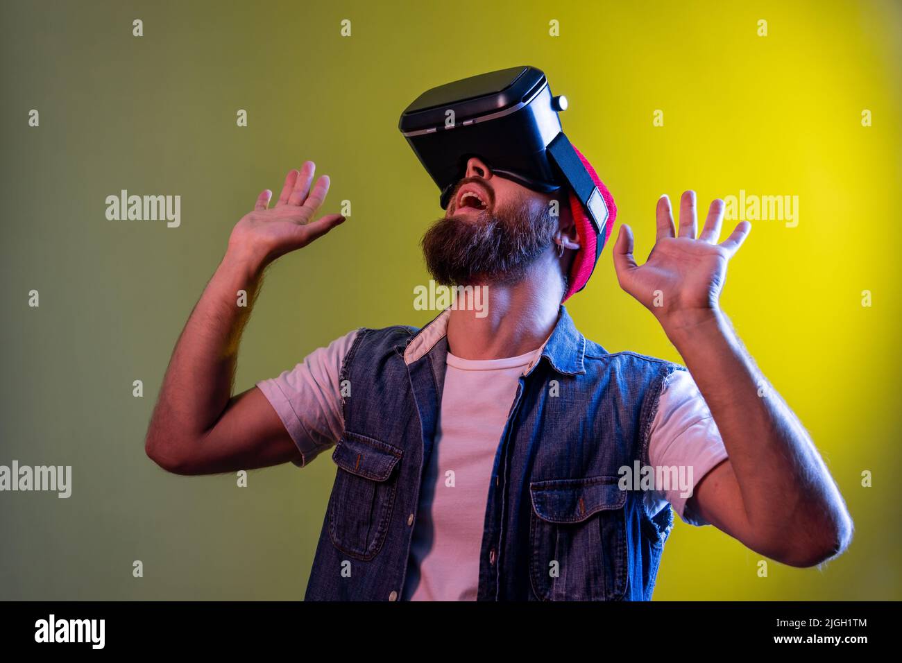 Impressed hipster guy with virtual reality glasses raised his hands up ...