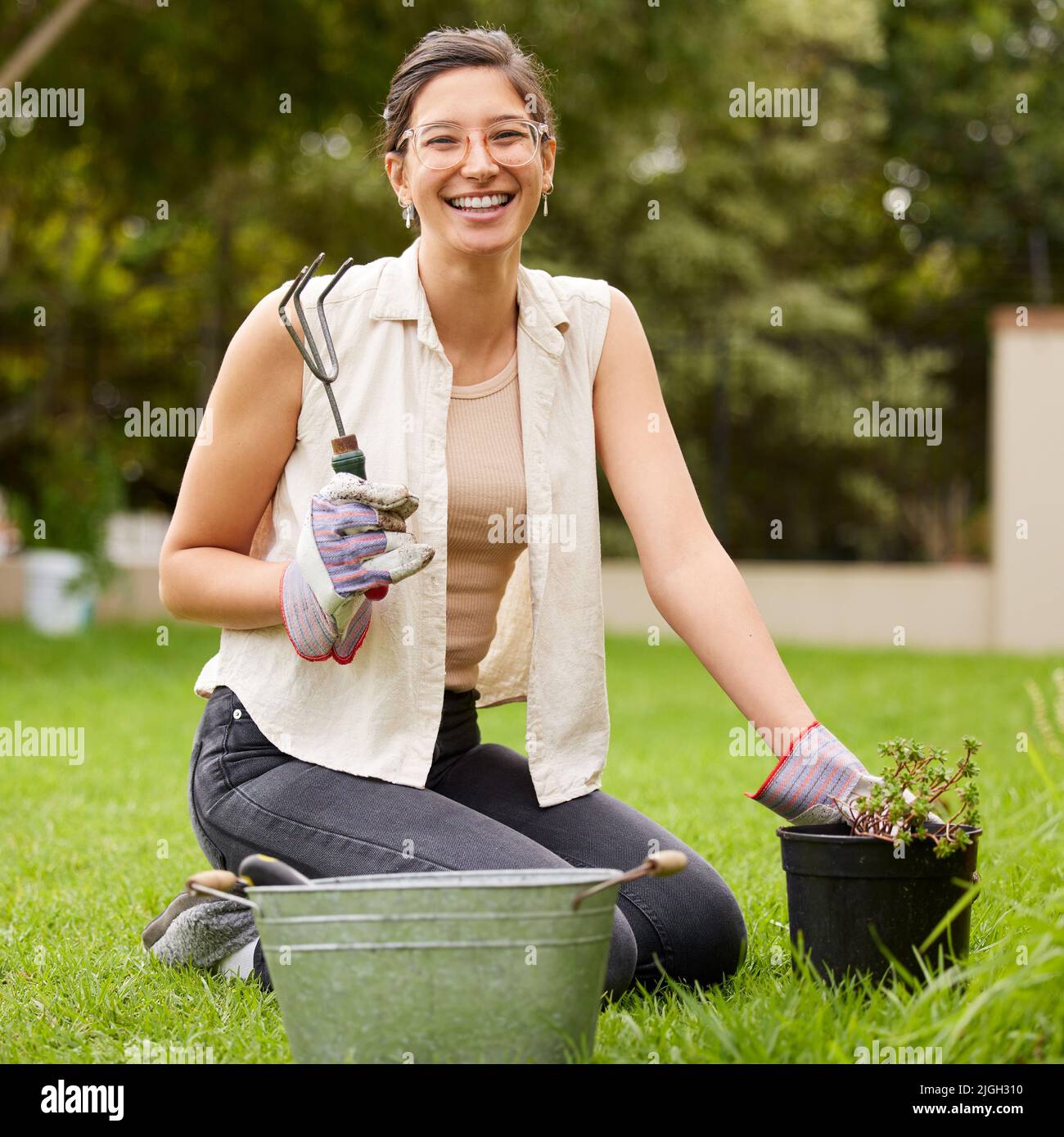 A buffet of growth just for me. Portrait of a smiling woman kneeling while doing some gardening in the backyard. Stock Photo