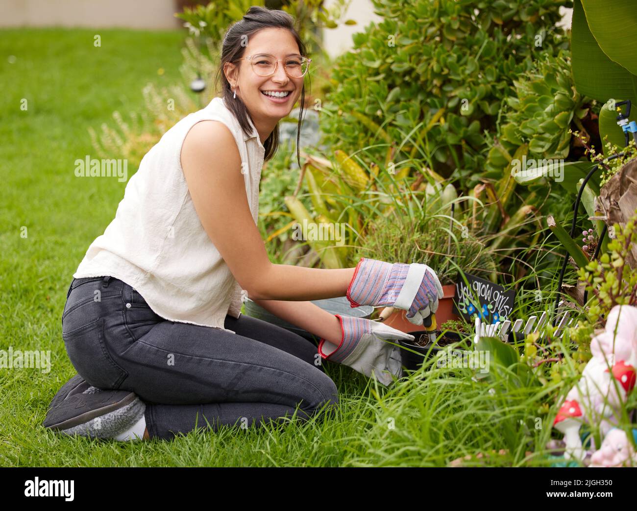 A peaceful heart, two green thumbs. Portrait of a smiling woman kneeling while doing some gardening in the backyard. Stock Photo