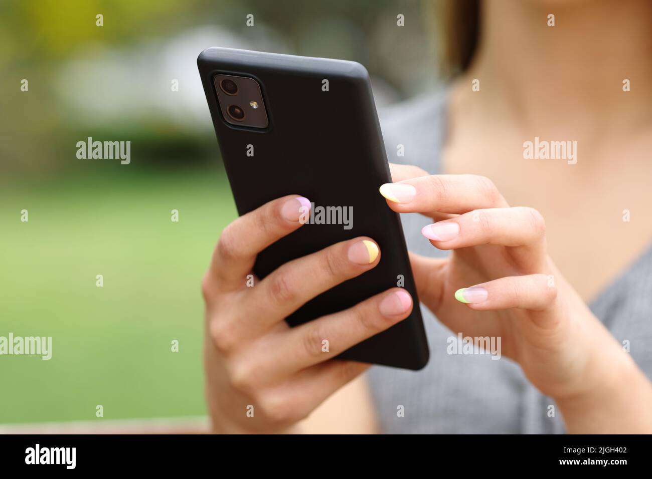 Woman hands close up using smart phone standing in a park Stock Photo