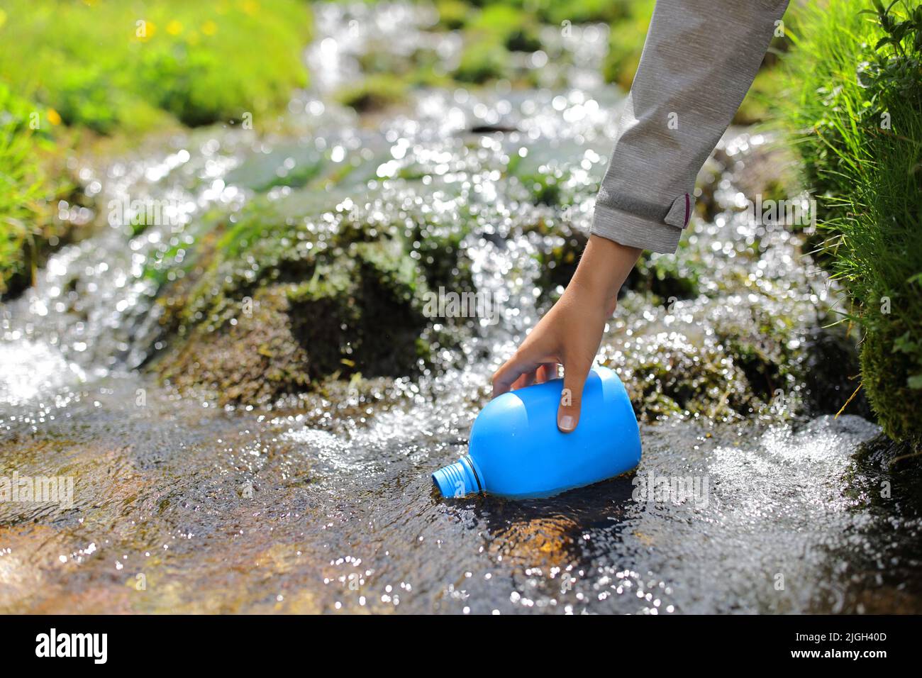 Clos eup of a hiker hand filling canteen with river water Stock Photo