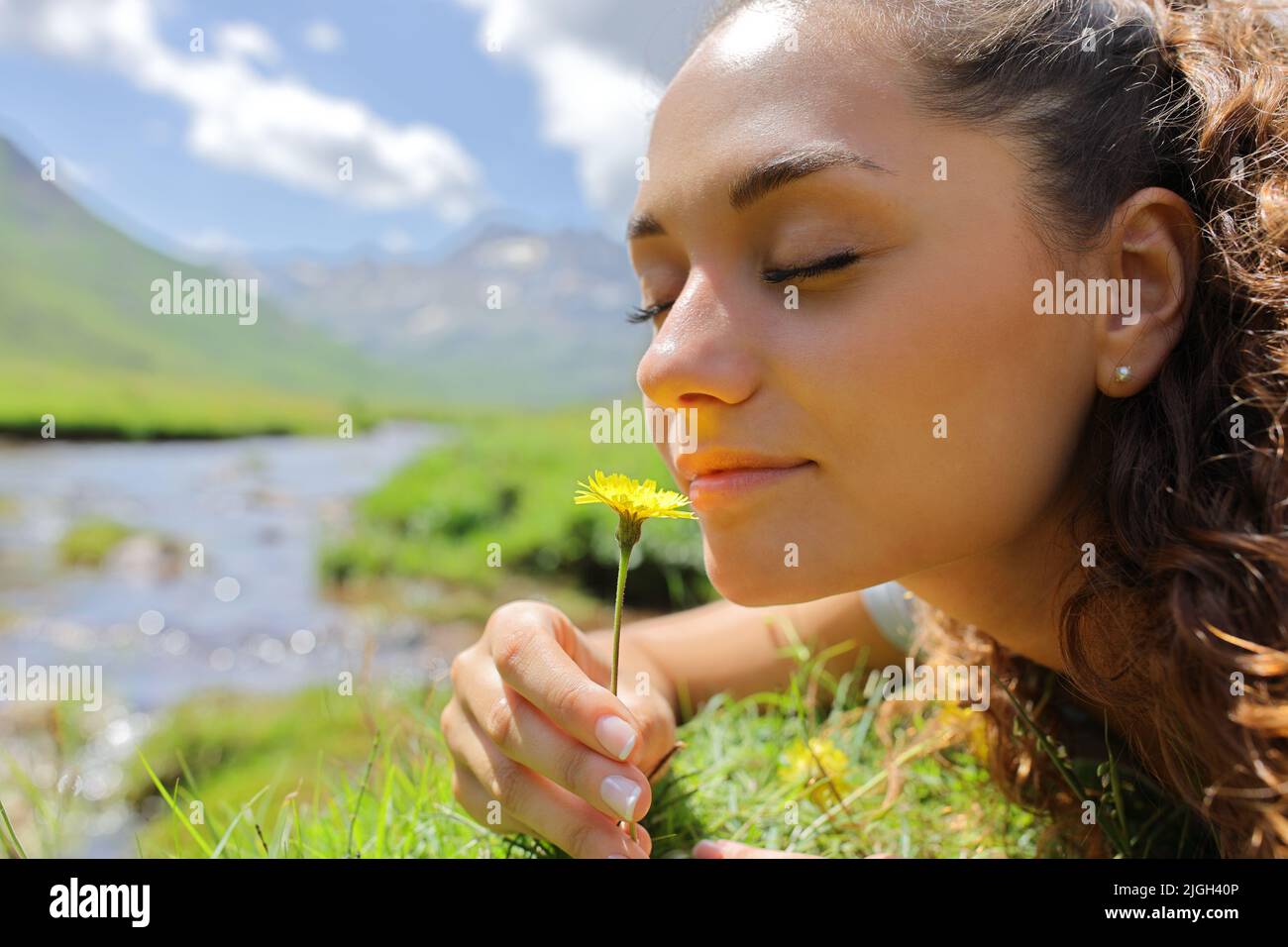 Portrait of a woman smelling a flower in the mountain in a riverside Stock Photo