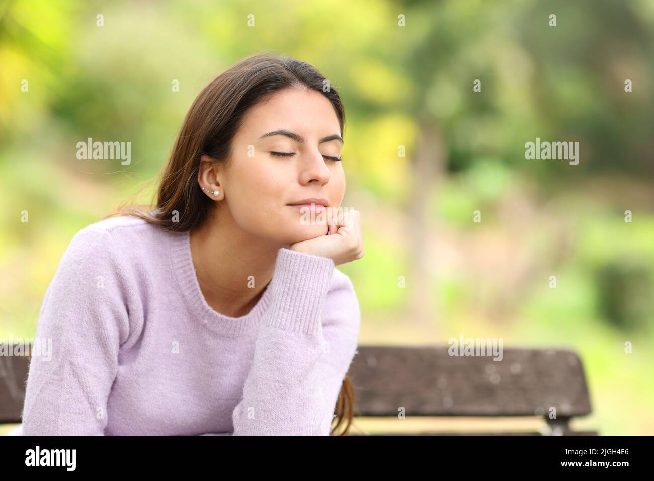 Teen relaxing and resting sitting on a bench in a green park Stock Photo
