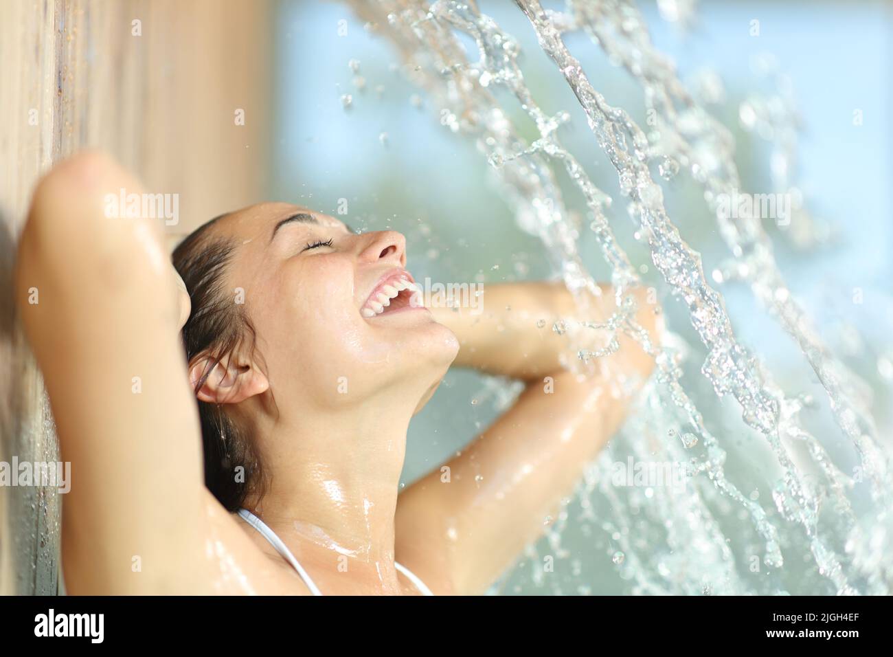 Happy woman enjoying and laughing under water jet in spa Stock Photo