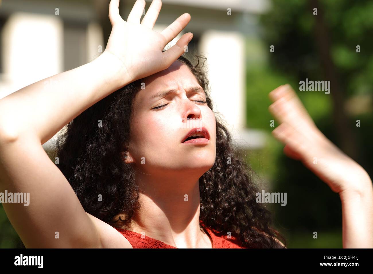 Overwhelmed woman suffering heat stroke a sunny day in a park Stock Photo