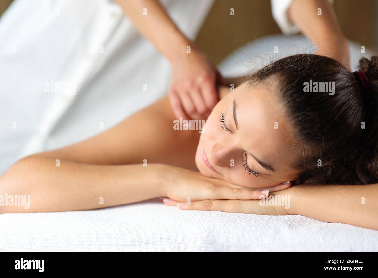 Woman relaxing with closed eyes and therapist massaging her in spa Stock Photo