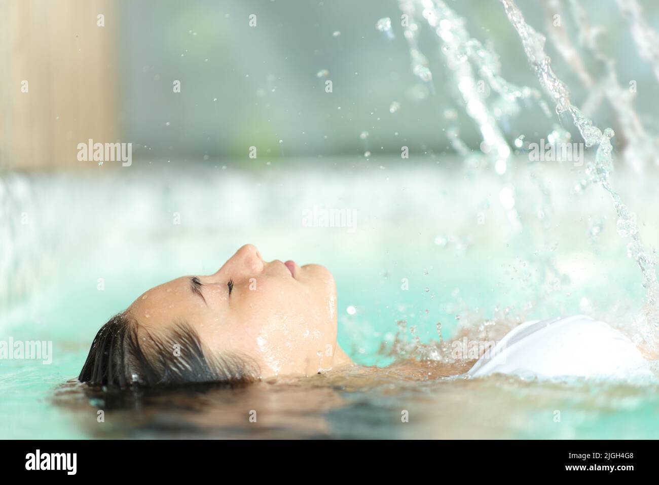 Side view portrait of a woman relaxing floating in spa pool water Stock Photo