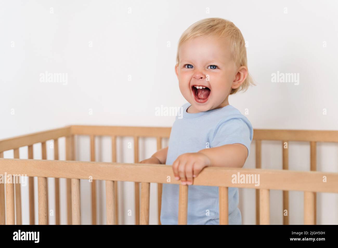Ten month old baby standing in crib with cheerful excited facial