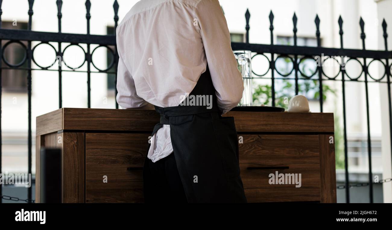 elegant waiter wearing black apron and white shirt Stock Photo - Alamy
