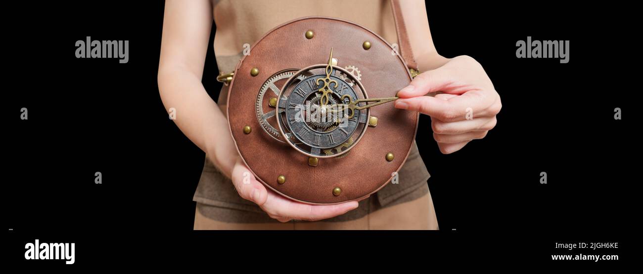Female demonstrating a circle steampunk leather bag with a clockwork against black background with copy space. Stock Photo
