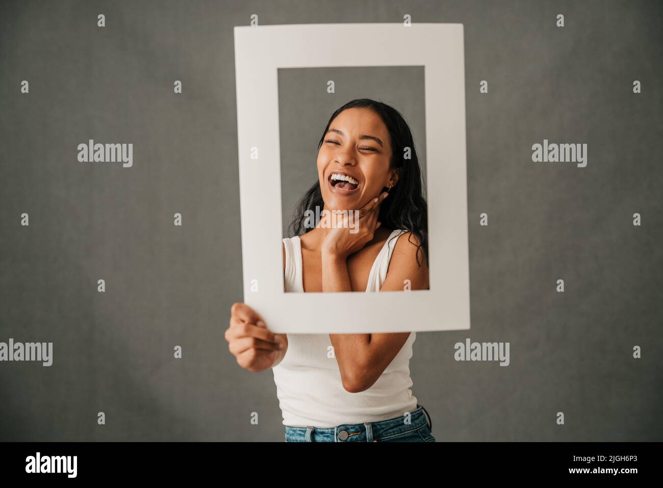 Laughing smiling close up of multiethnic female holding a frame  Stock Photo
