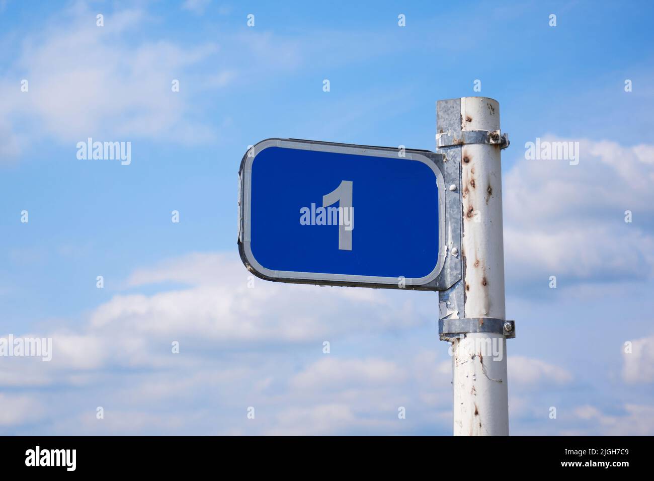 Road sign 1 km against the blue sky with white clouds Stock Photo