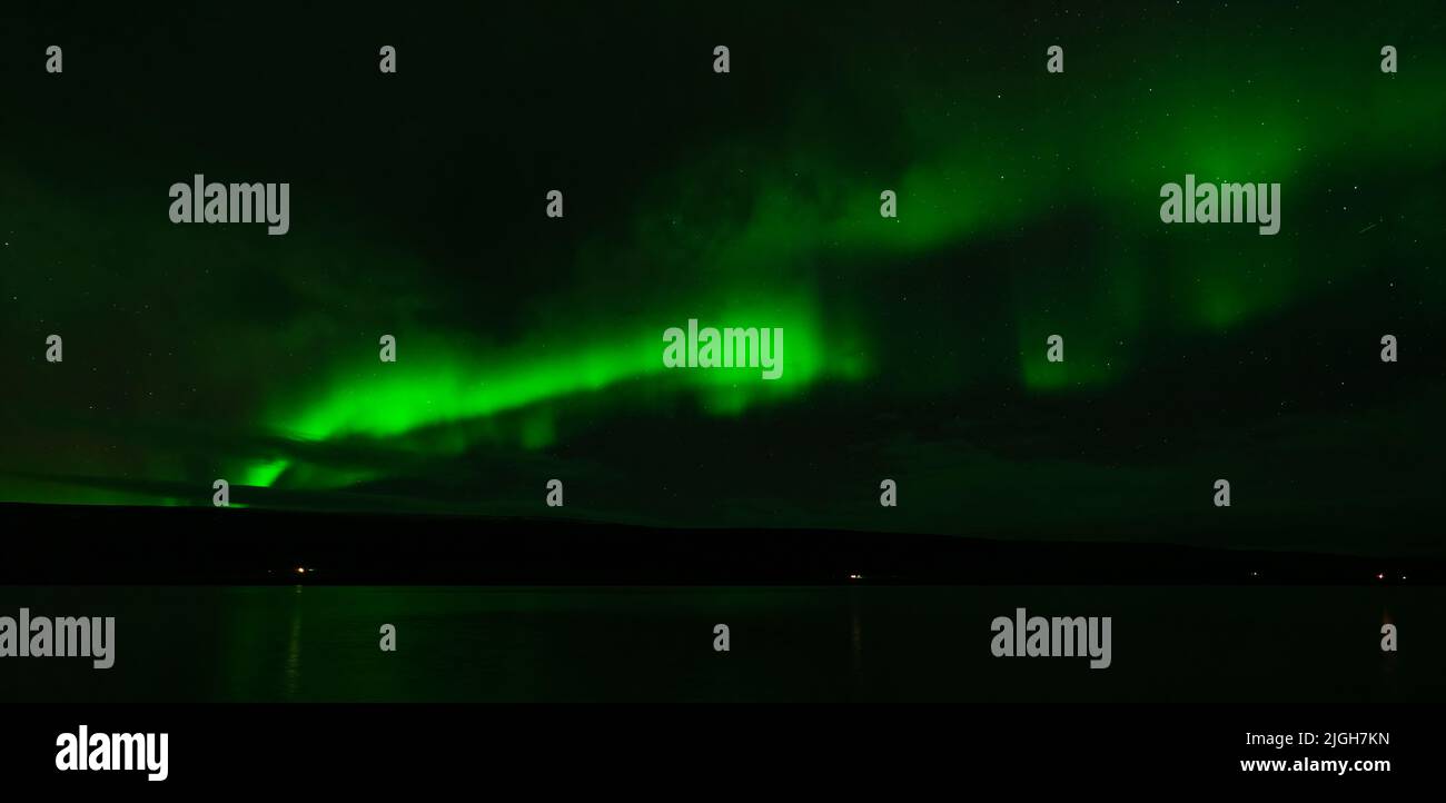 Northern lights over the plain lake with green lights Stock Photo