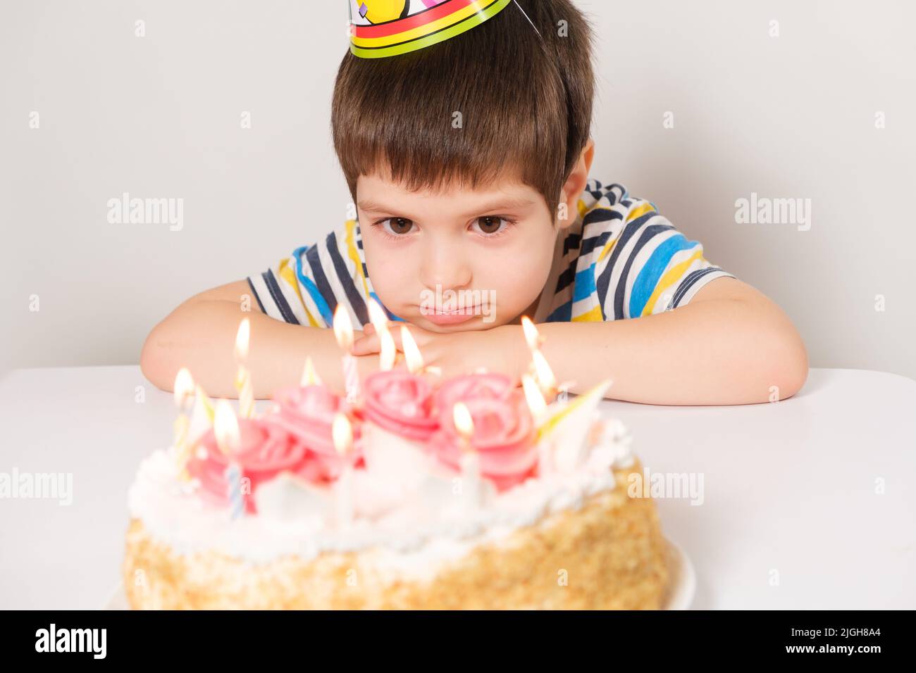 A handsome boy celebrates a birthday, sits in front of a cake with ...