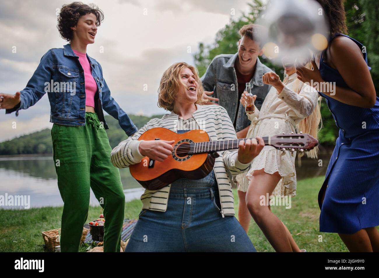 Group of young friends having fun on picnic near a lake, laughing ...