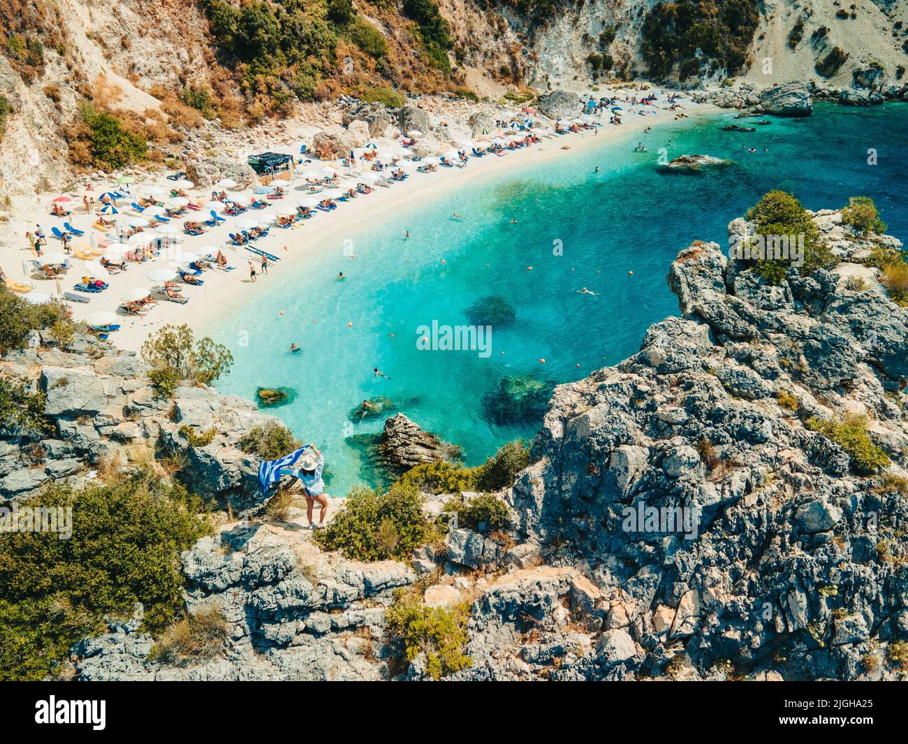 happy woman in blue swimsuit holding greece flag at the top of the