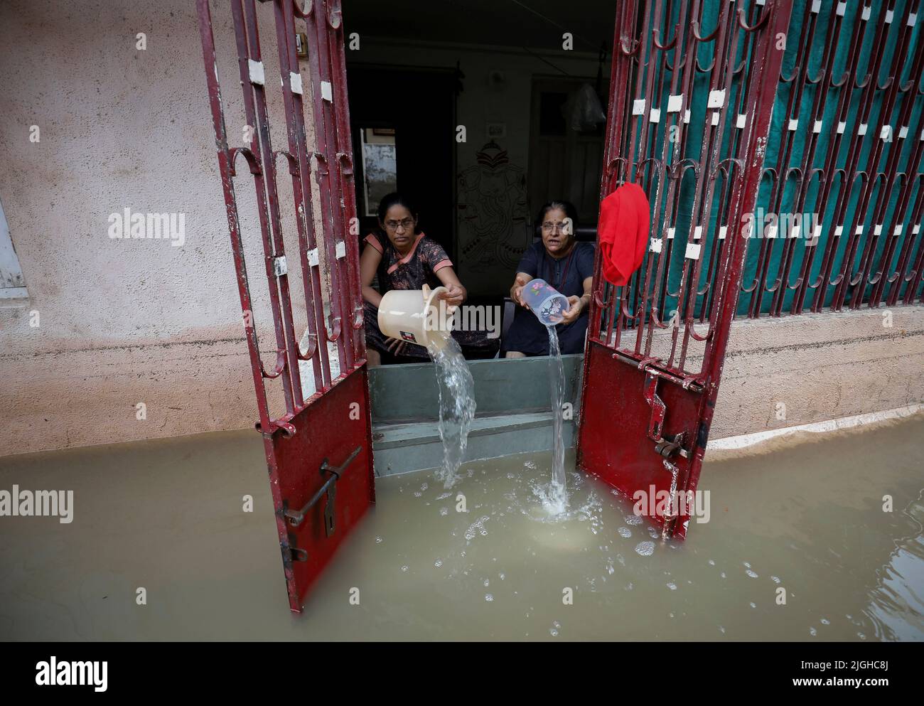 Women remove water from their flooded house after heavy rains in Ahmedabad, India, July 11, 2022. REUTERS/Amit Dave Stock Photo