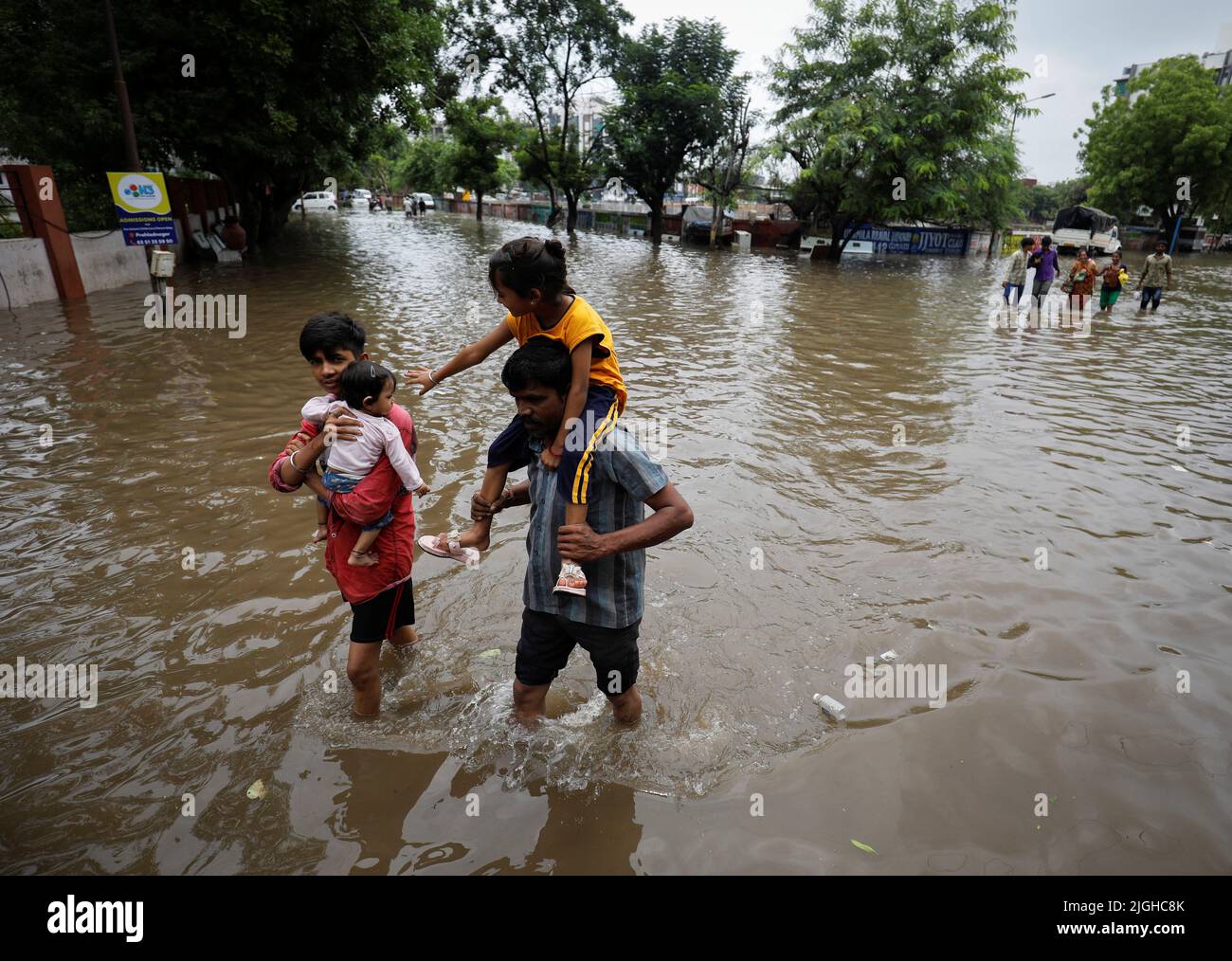 People walk through a flooded street after heavy rains in Ahmedabad, India, July 11, 2022. REUTERS/Amit Dave Stock Photo