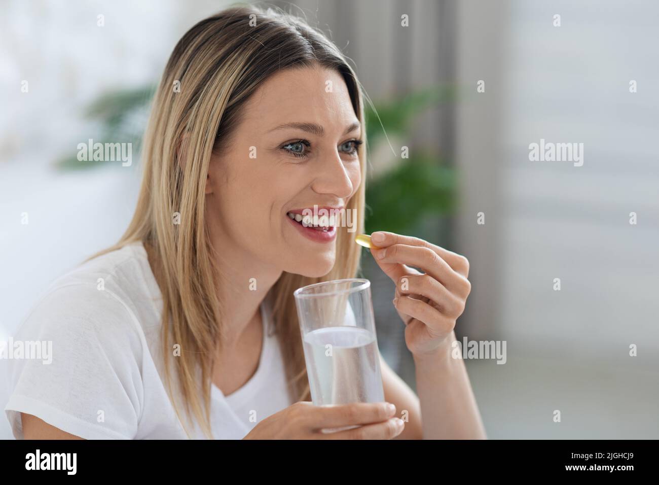 Attractive millennial woman taking medicine and looking at copy space Stock Photo